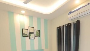 A bedroom with a bed, a nightstand, a ceiling fan, and a wall-mounted air conditioner. - Mandav Hills Resort (Dhar)