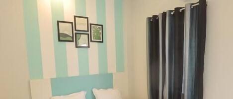 A bedroom with a bed, a nightstand, a ceiling fan, and a wall-mounted air conditioner.