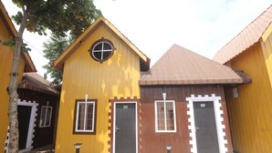 A building with a yellow facade, brown roof, and white trim around windows and doors. - Mandav Hills Resort (Dhar)
