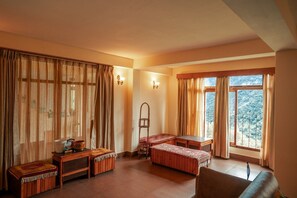A cozy room with a wooden bench, a small table, and a chair. There are curtains on the windows, and a balcony with a railing is visible. - Springhill Farmstead. Wake Up to Kanchenjunga – Your Luxury Escape in Pelling (Pelling)