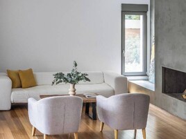 Una sala de estar moderna con un sofá, dos sillones, una mesa de centro y una chimenea.