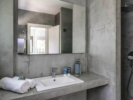 Un baño con un lavamanos blanco, un espejo grande y una toalla sobre la encimera.
