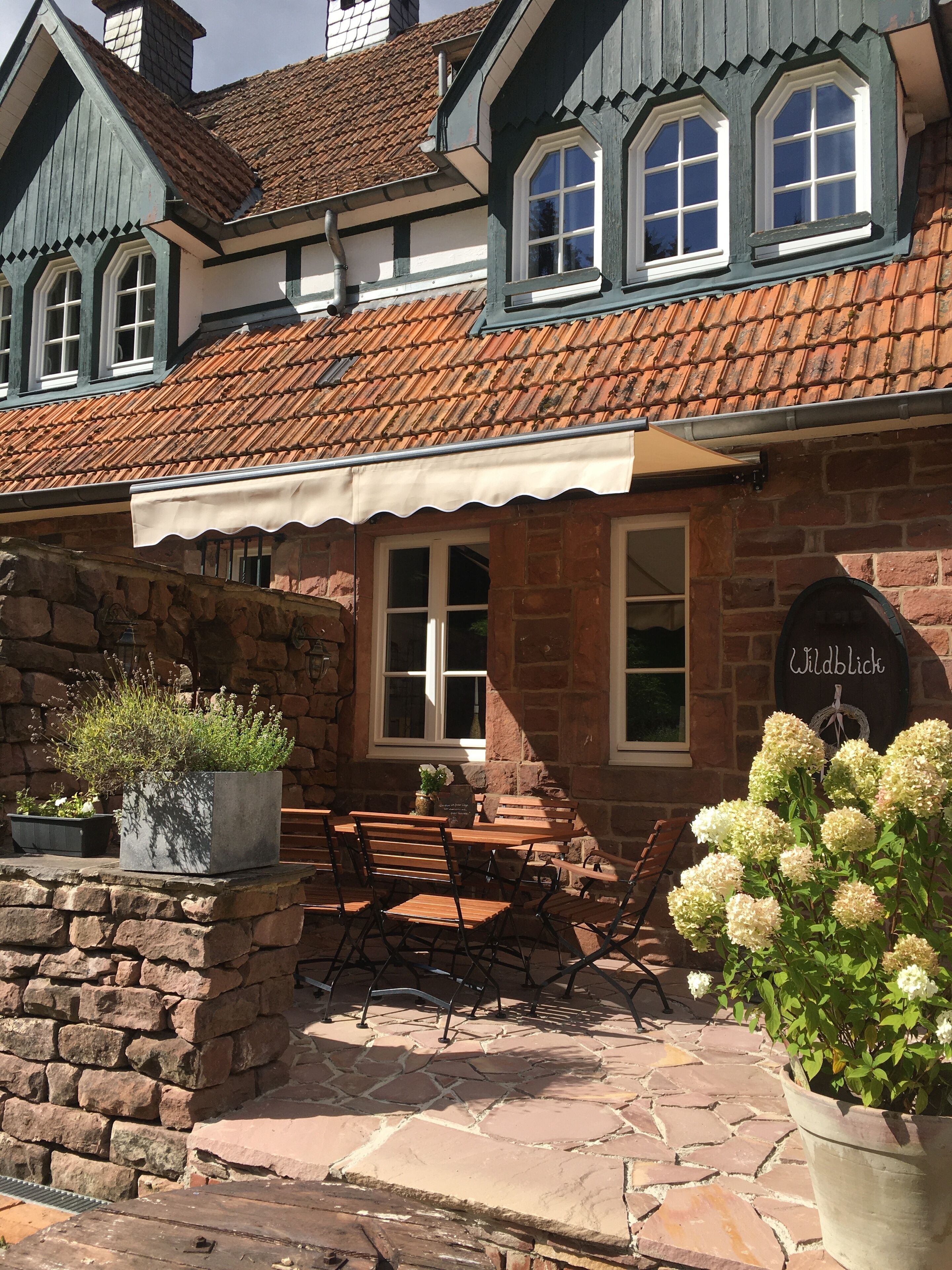 A traditional building with a stone facade, wooden benches, and a sign reading "Wildblick".