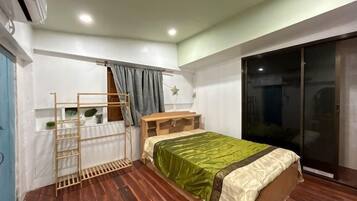 A bedroom with a bed, a wooden ladder, a desk, and a sliding glass door.