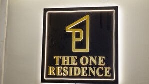 Opastekyltti, jossa lukee teksti ”THE ONE RESIDENCE” ja on tyylitelty ’P’-kirjaimen logo.
