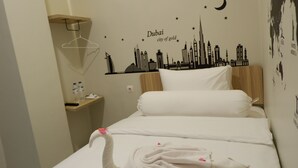 Hotellihuone, jossa on sänky, yöpöytä ja seinätarra, jossa on kuvattuna Dubain kaupunkikuva.