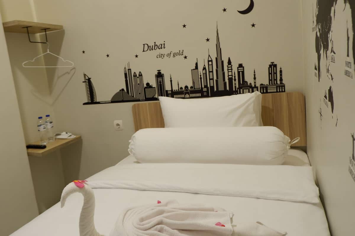 Habitació d'hotel amb un llit, una petita taula de nit i un adhesiu mural de l'horitzó de Dubai.