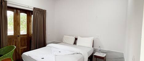 A bedroom with a bed, a wooden nightstand, a green chair, and a ceiling fan.