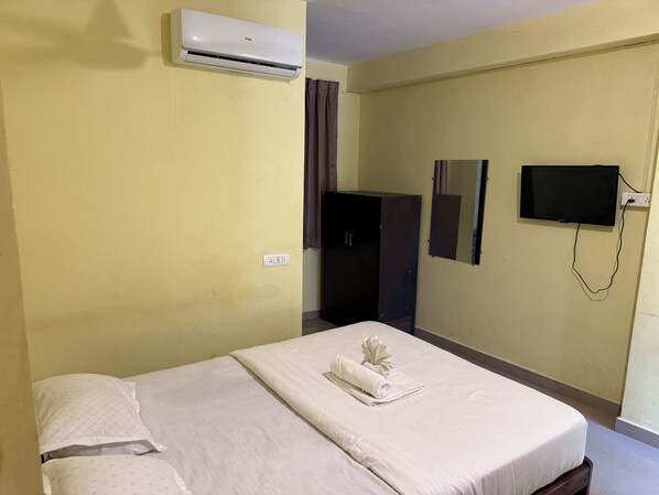 Una habitación de hotel con cama, aire acondicionado, armario, espejo y televisión.