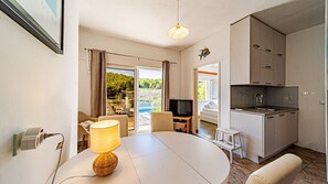 Una habitación moderna con una mesa de comedor, televisor y área de cocina.