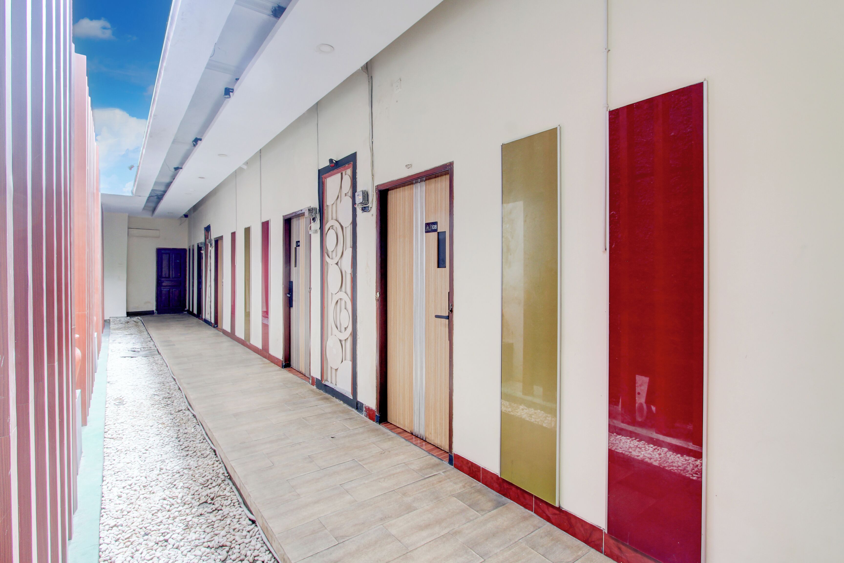 Un pasillo con puertas que dan a habitaciones, suelo de baldosas e iluminación empotrada en el techo.