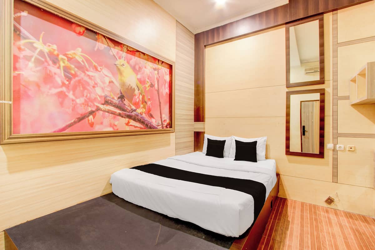A hotel room with a large bed, a wooden headboard, a large mirror, and a painting of birds on a branch.
