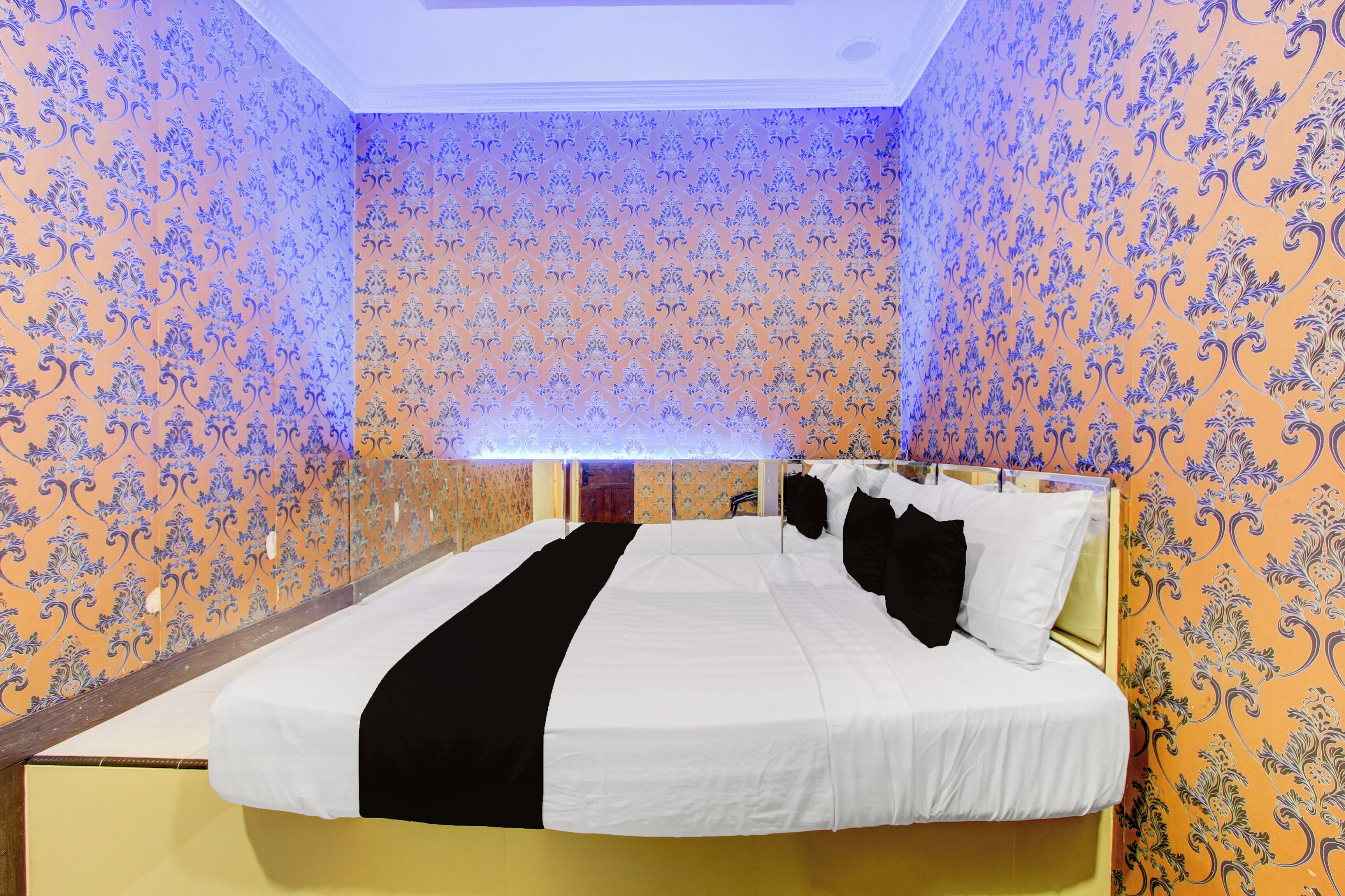 Una habitación de hotel con una cama grande, cabecera y papel tapiz estampado.