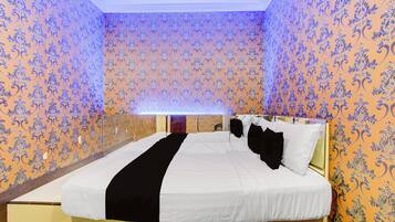 Una habitación de hotel con una cama grande, cabecera y papel tapiz estampado.