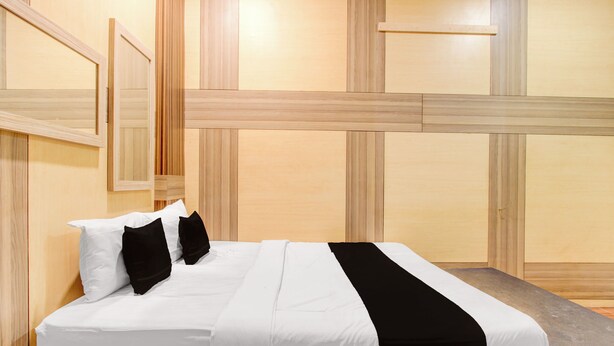 Een hotelkamer met een groot bed, houten lambrisering en een zwart-wit sprei.