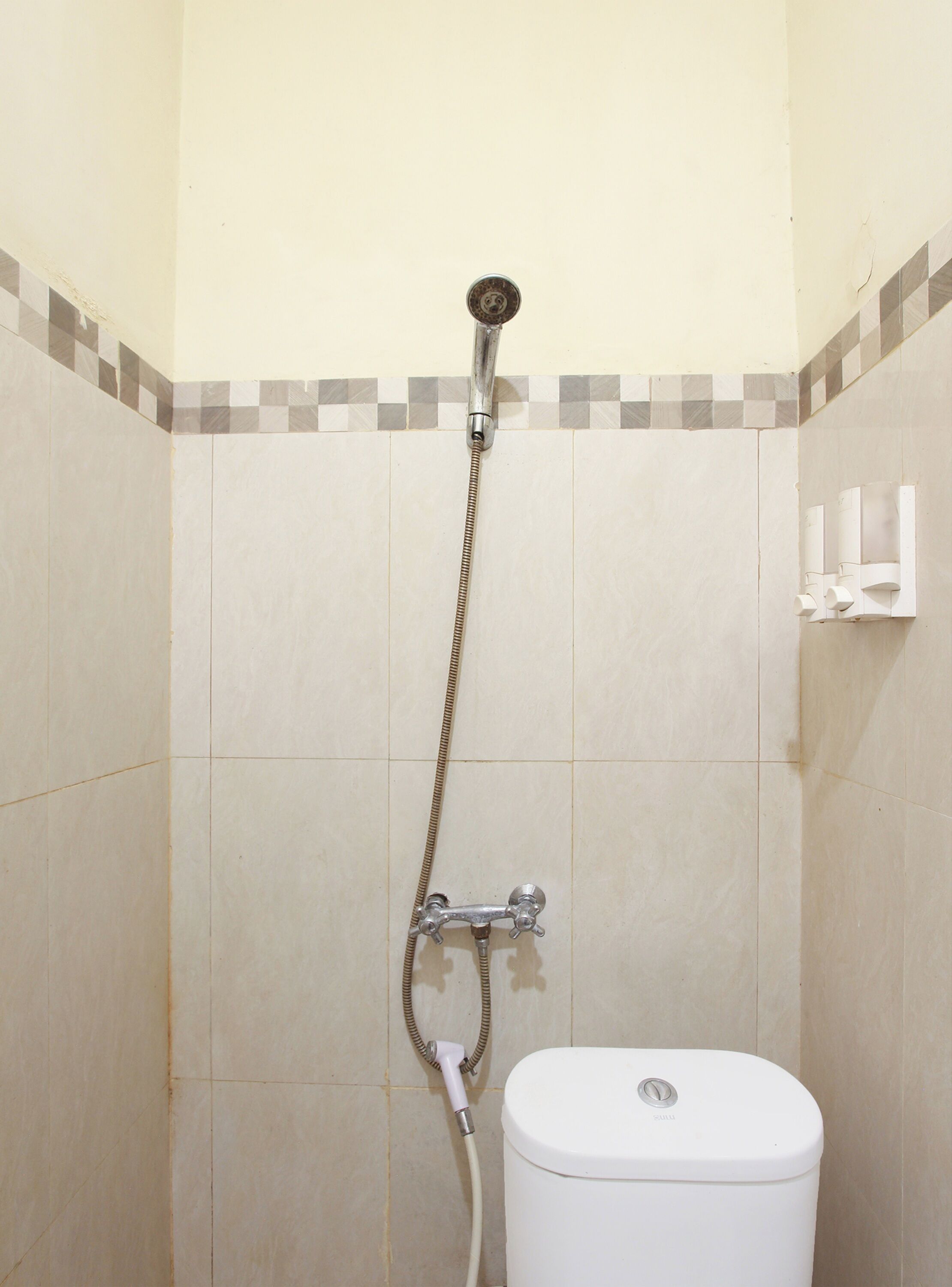 Ein Badezimmer mit Dusche, Toilette und gefliesten Wänden.