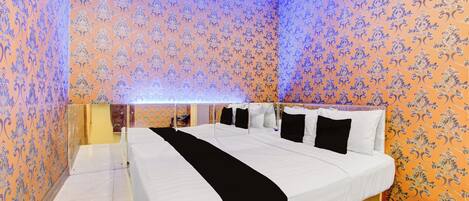 Una habitación de hotel con una cama grande, ropa de cama blanca y papel tapiz estampado.