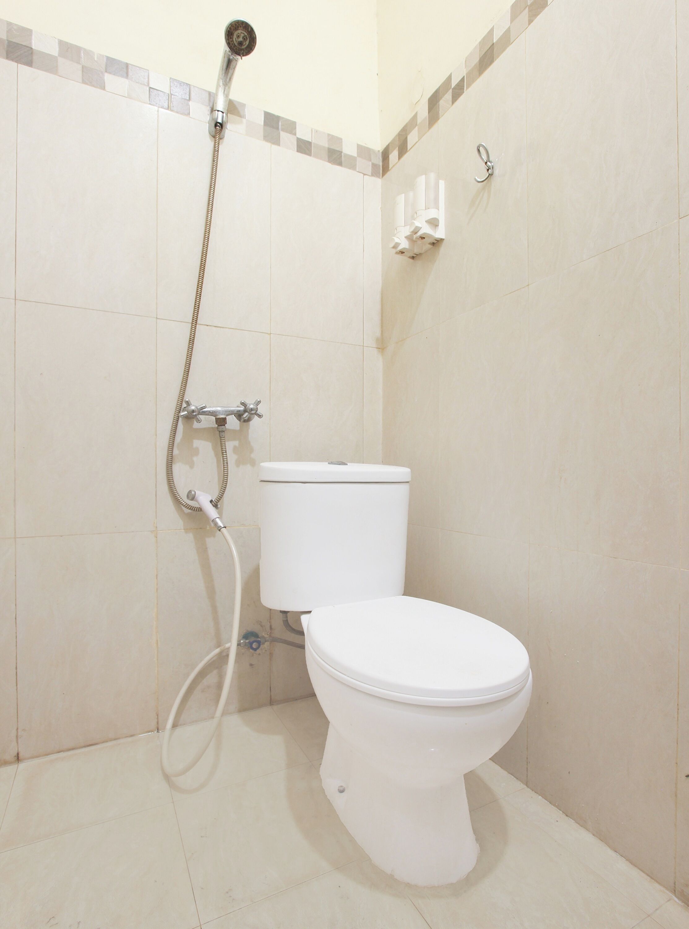 A bathroom with a toilet, a shower, and a tiled wall.