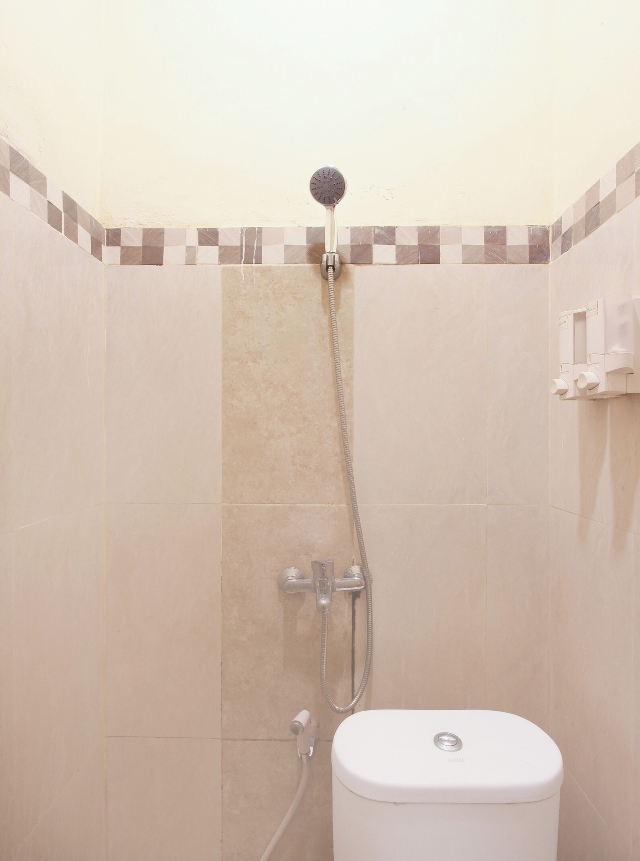 A bathroom with a shower, toilet, and hand dryer.