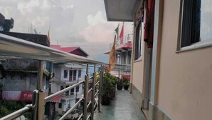 A narrow corridor with a green floor, metal railings, and a building on one side. - Sherpa Residency (Kalimpong)