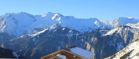 Une station de montagne où les bâtiments sont recouverts de neige et d’où l’on a une vue dégagée sur les sommets environnants.