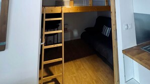 A compact room with a bunk bed, a small desk, and a kitchenette area. - Alpine Escape (Huez)