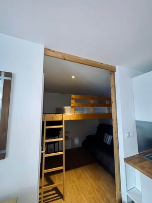 Habitació petita amb literes, un escriptori petit i una zona de cuina equipada.