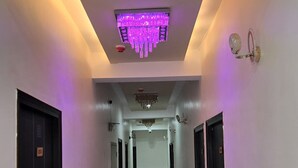 A hallway with a marble floor, black doors, and a ceiling with a purple light fixture.