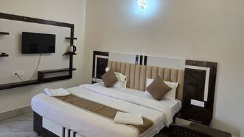 A modern hotel room with a large bed, a ceiling fan, a flat-screen TV, and a bedside table.