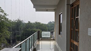 A corridor with a glass railing, a green mat, and a door with a window.