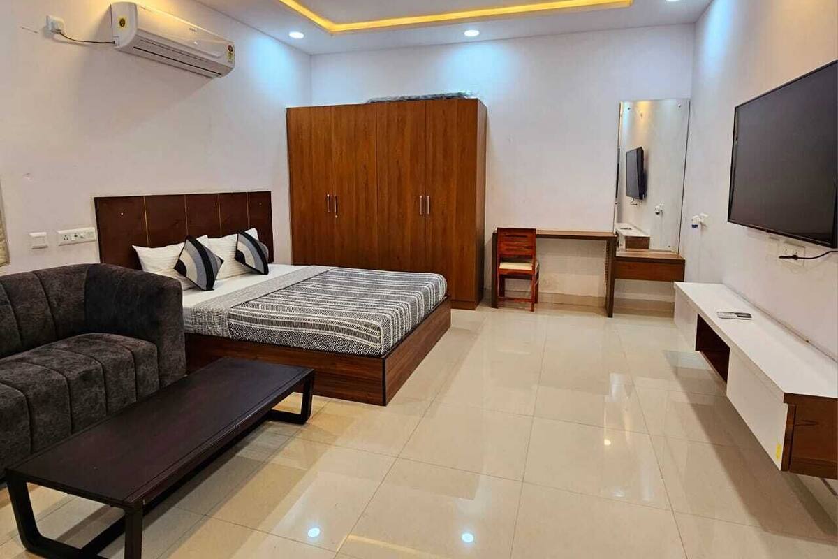 A modern bedroom with a bed, a sofa, a TV, and a wardrobe.