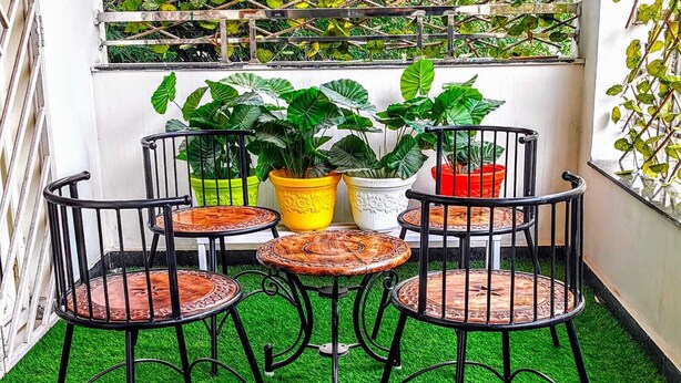 A small outdoor seating area with four metal chairs and a table, surrounded by potted plants. - Crescent Stays Madhapur  (Hyderabad)