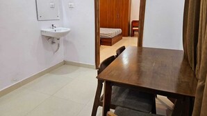 A small, clean room with a wooden table, a single chair, a sink, and a wardrobe. - Crescent Stays Madhapur  (Hyderabad)