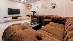 A modern living room with a sectional sofa, a flat-screen TV, and decorative wall art. - Crescent Stays Madhapur  (Hyderabad)