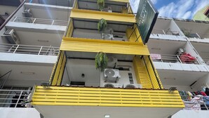 A multi-story building with balconies, air conditioning units, and a sign indicating a taxi service. - LimeTree Loft Guesthouse (Patong)