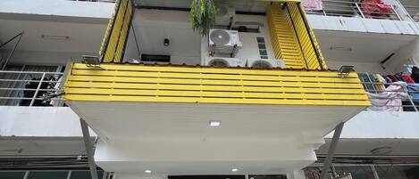 Un edificio de varios pisos con balcones, unidades de aire acondicionado y un letrero que indica servicio de taxis.