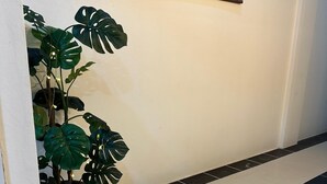 A hallway with a potted monstera plant, a black and white tiled floor, and a painting of horses on the wall. - LimeTree Loft Guesthouse (Patong)