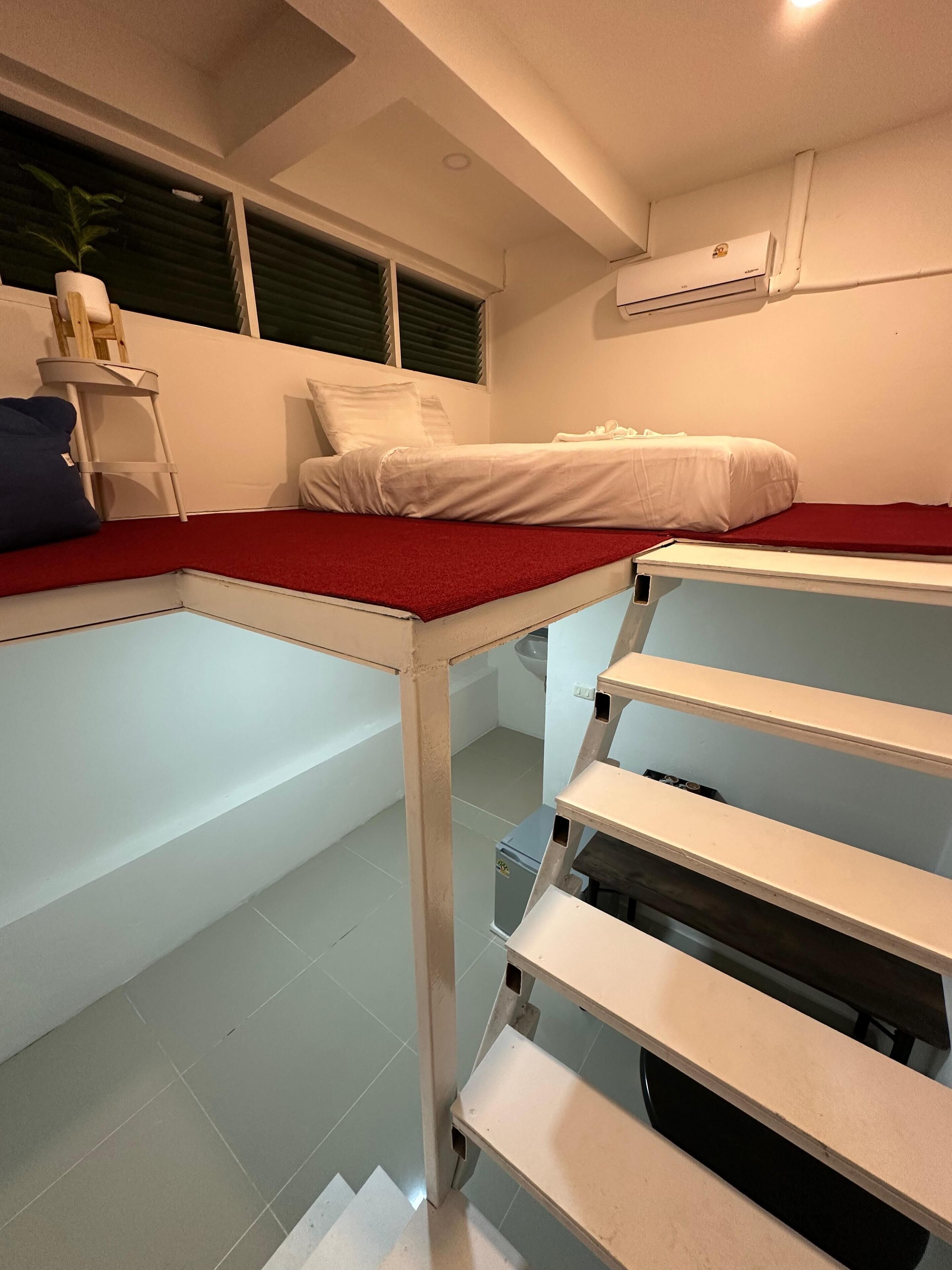 A compact room with a bunk bed, a small table, and a shelf unit.