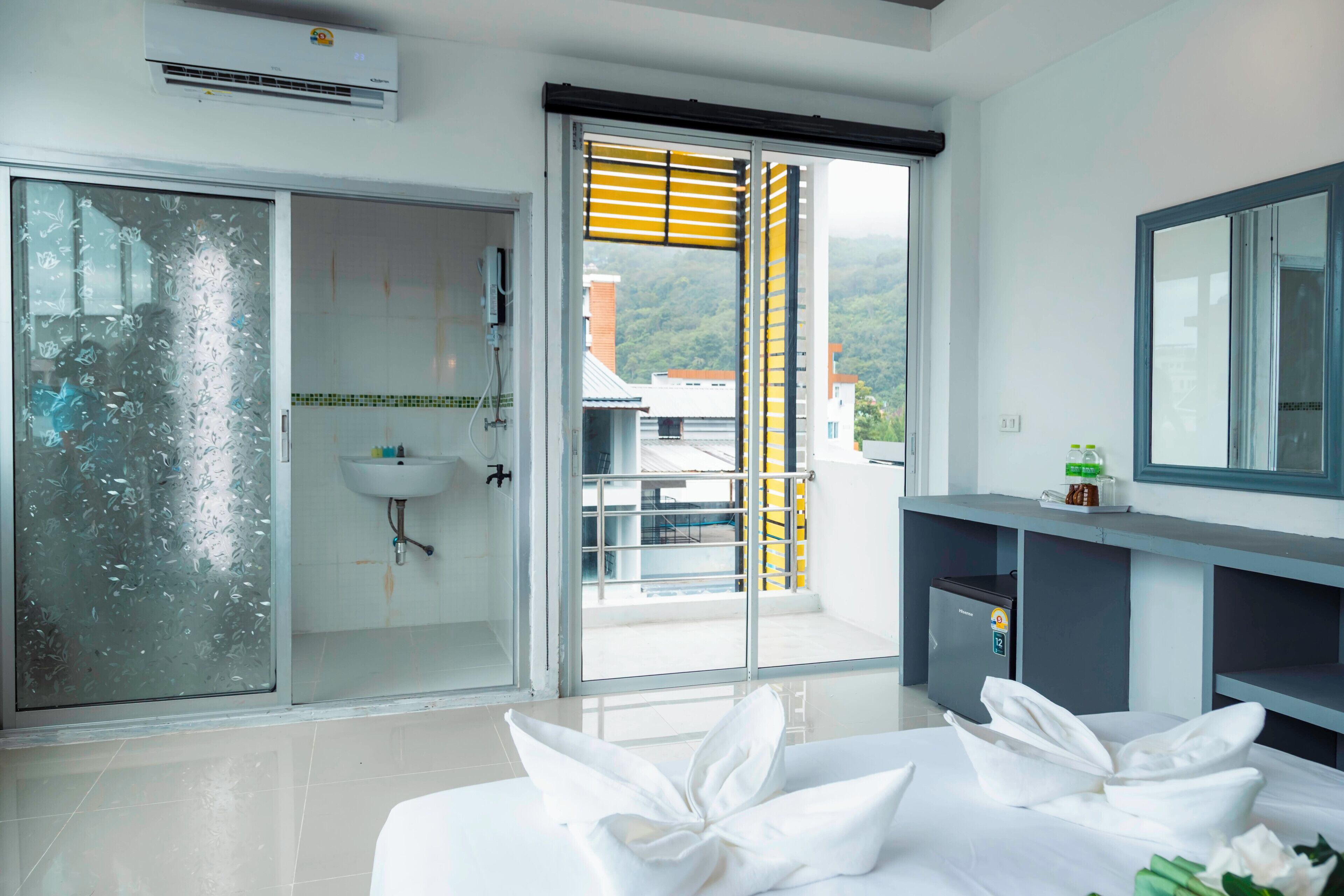 A hotel room with a sliding glass door to a balcony, a sink, a small cabinet, and a mirror.