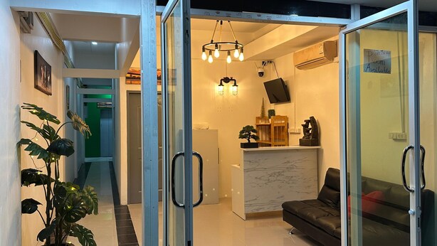 A modern living area with a glass door leading to a kitchen, a sofa, a potted plant, and a marble countertop. - LimeTree Loft Guesthouse (Patong)