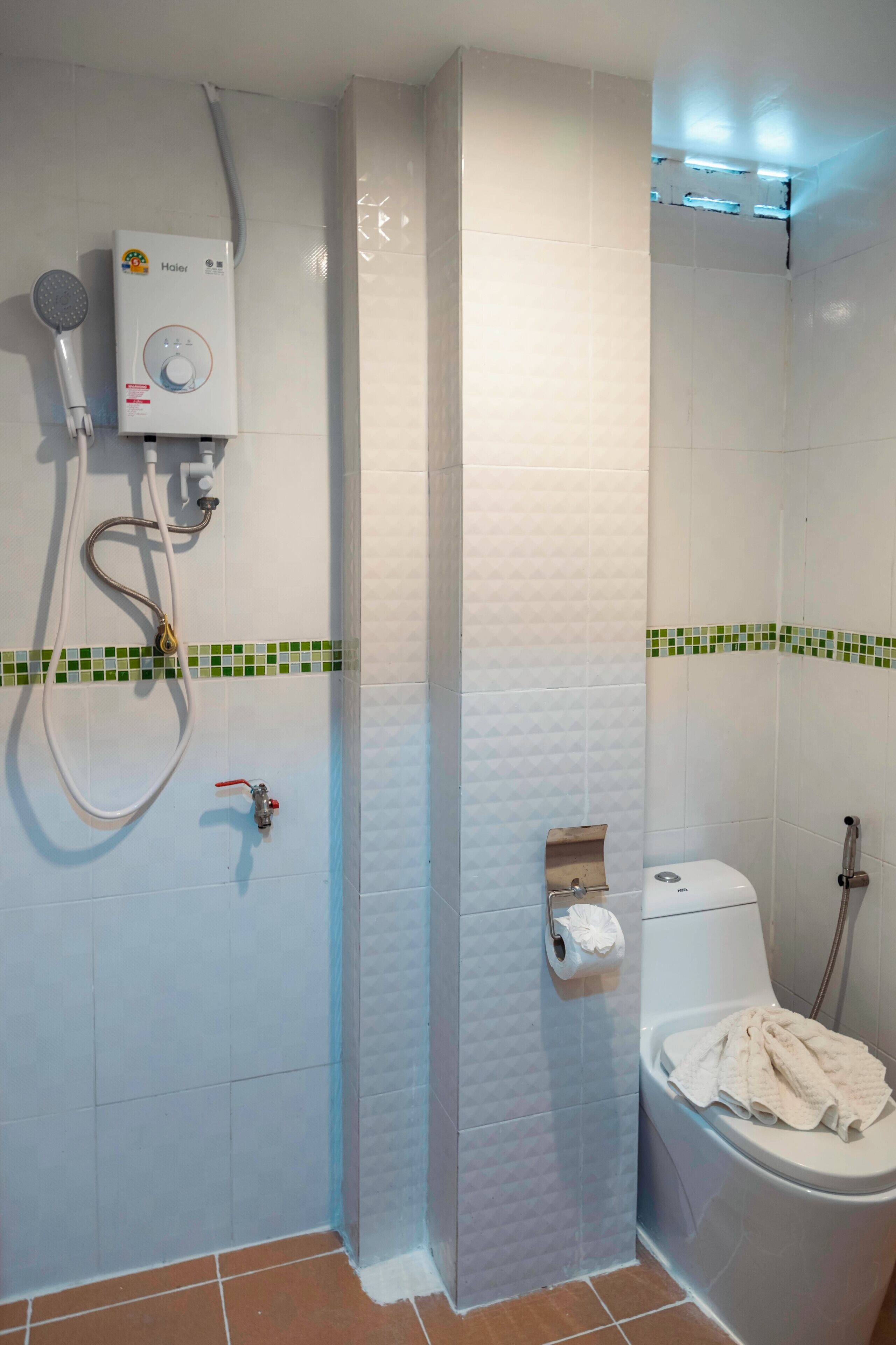 A bathroom with a shower, toilet, and a towel rack.
