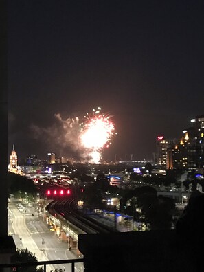 A nighttime cityscape with fireworks in the sky, a prominent clock tower, and a busy street below. - Hidden Gem on Flinders Street - Renovated CBD Studio (Melbourne)