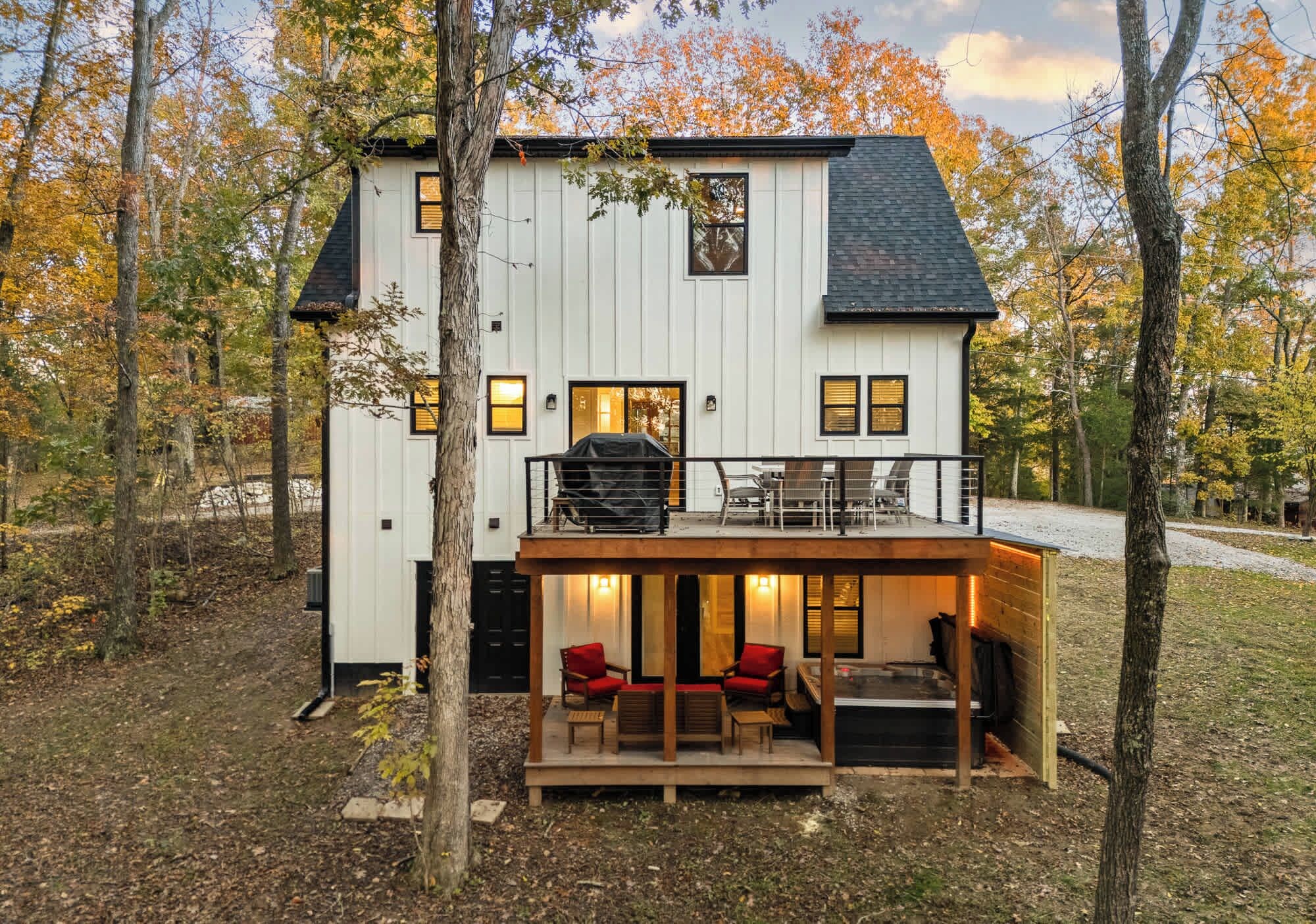 Une maison à deux étages dotée d’une terrasse, d’un espace salon extérieur et d’un coin barbecue.