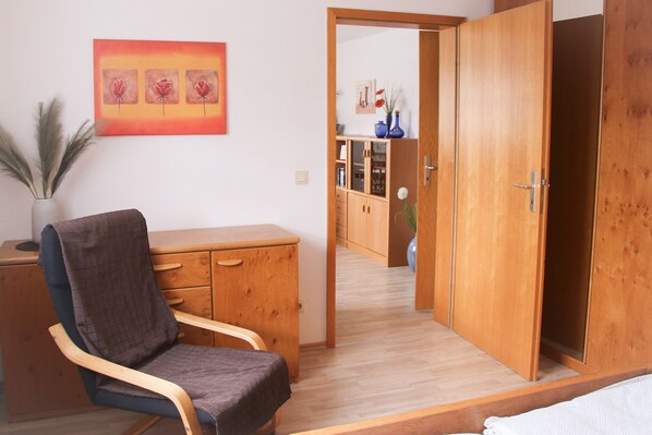 Ein Zimmer mit einem Holzschrank, einem Stuhl, einem Schreibtisch und einem Bild an der Wand.