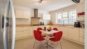Una cocina moderna con armarios blancos, estufa y comedor con sillas rojas.