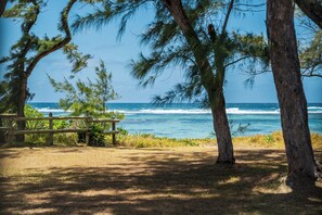 A beach view with a wooden bench and trees. - Villa Lagoon by Oazure (Trou d'eau douce)