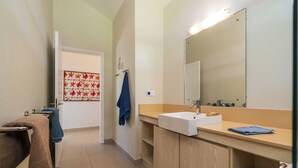 Un baño con un lavamanos blanco, un espejo y un perchero para toallas.