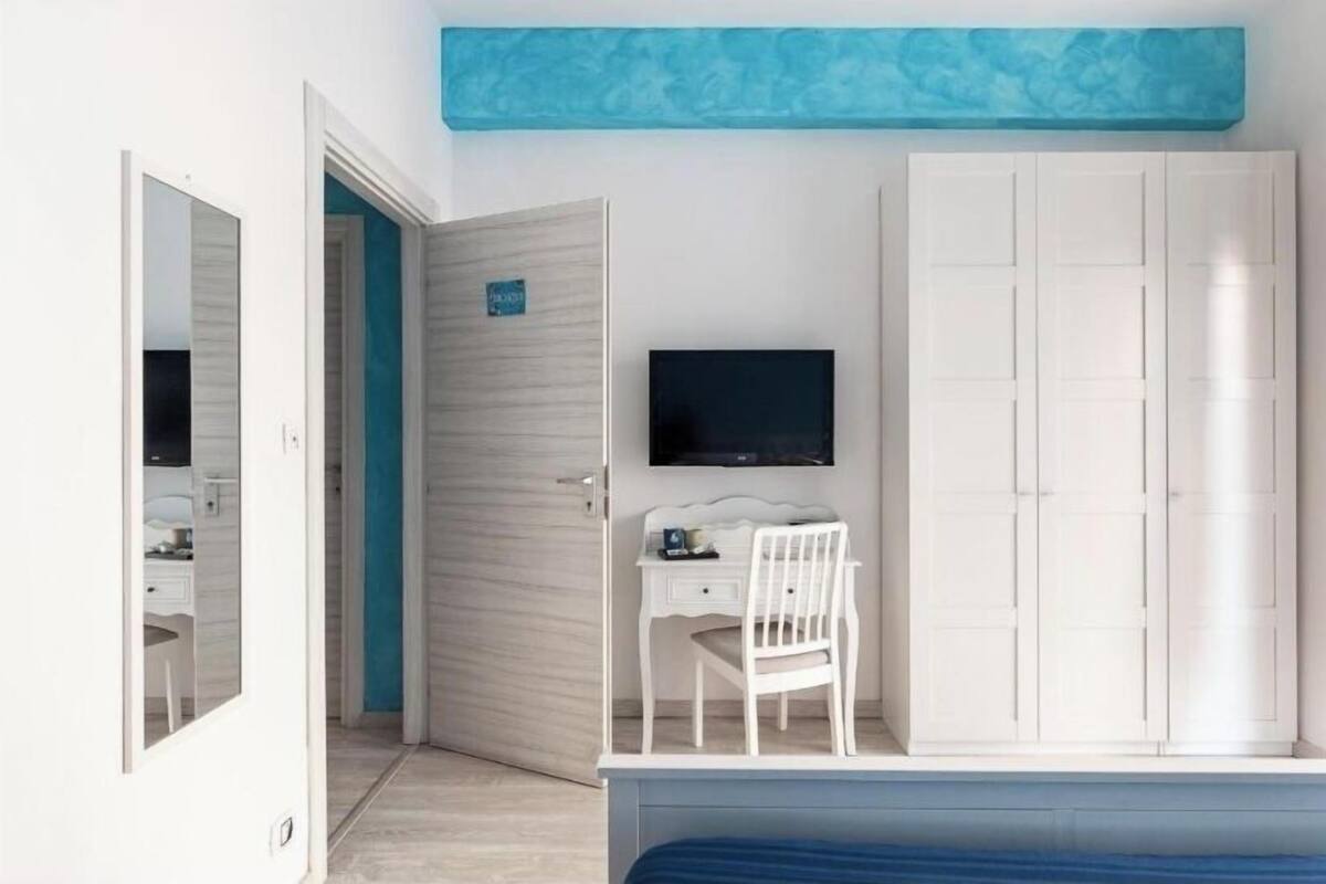 Een slaapkamer met een bed, een bureau, een stoel, een kledingkast en een televisie.