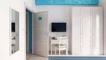 A bedroom with a bed, a desk, a chair, a wardrobe, and a television.