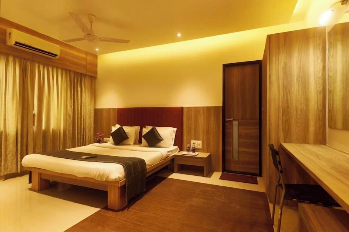 A modern hotel room with a wooden bed, a nightstand, a wardrobe, and a ceiling fan.